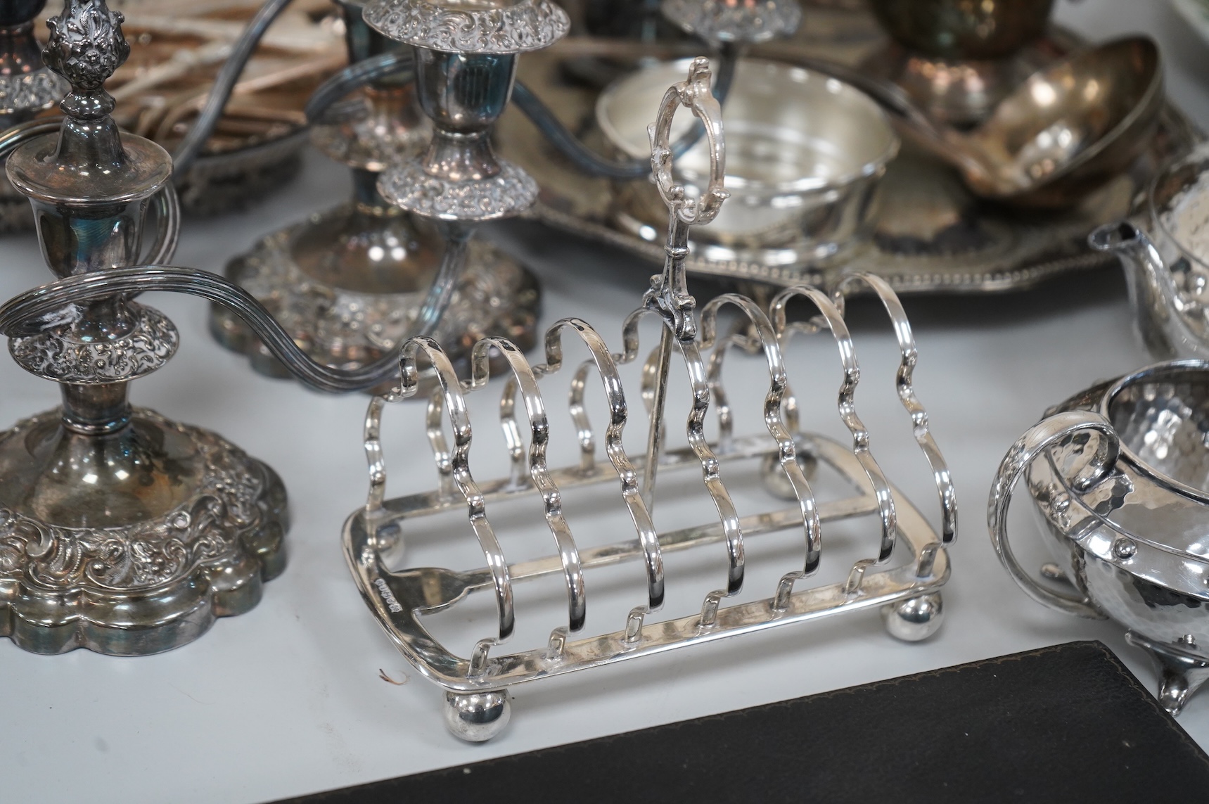 A collection of silver plate to include cased dessert forks, a hammered tea pot, pair of candlesticks and a salver
